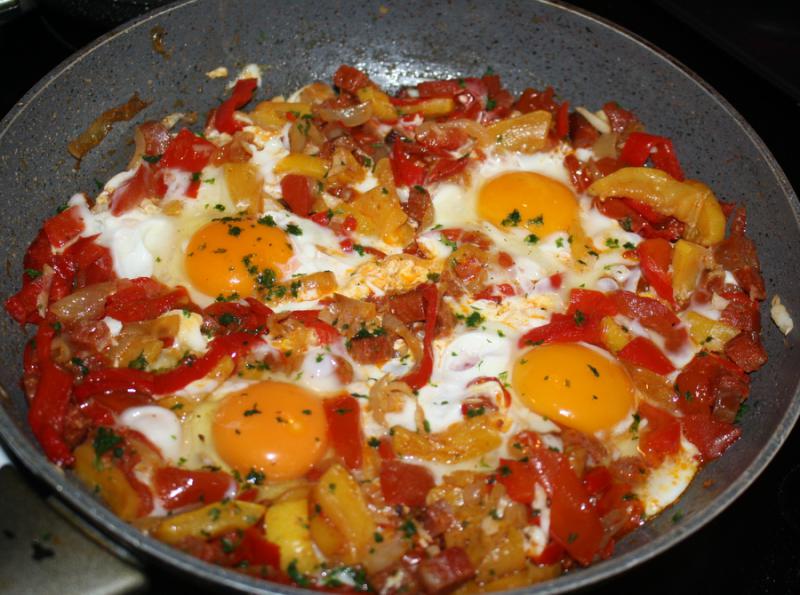 ufs sur lit de poivrons et tomates.